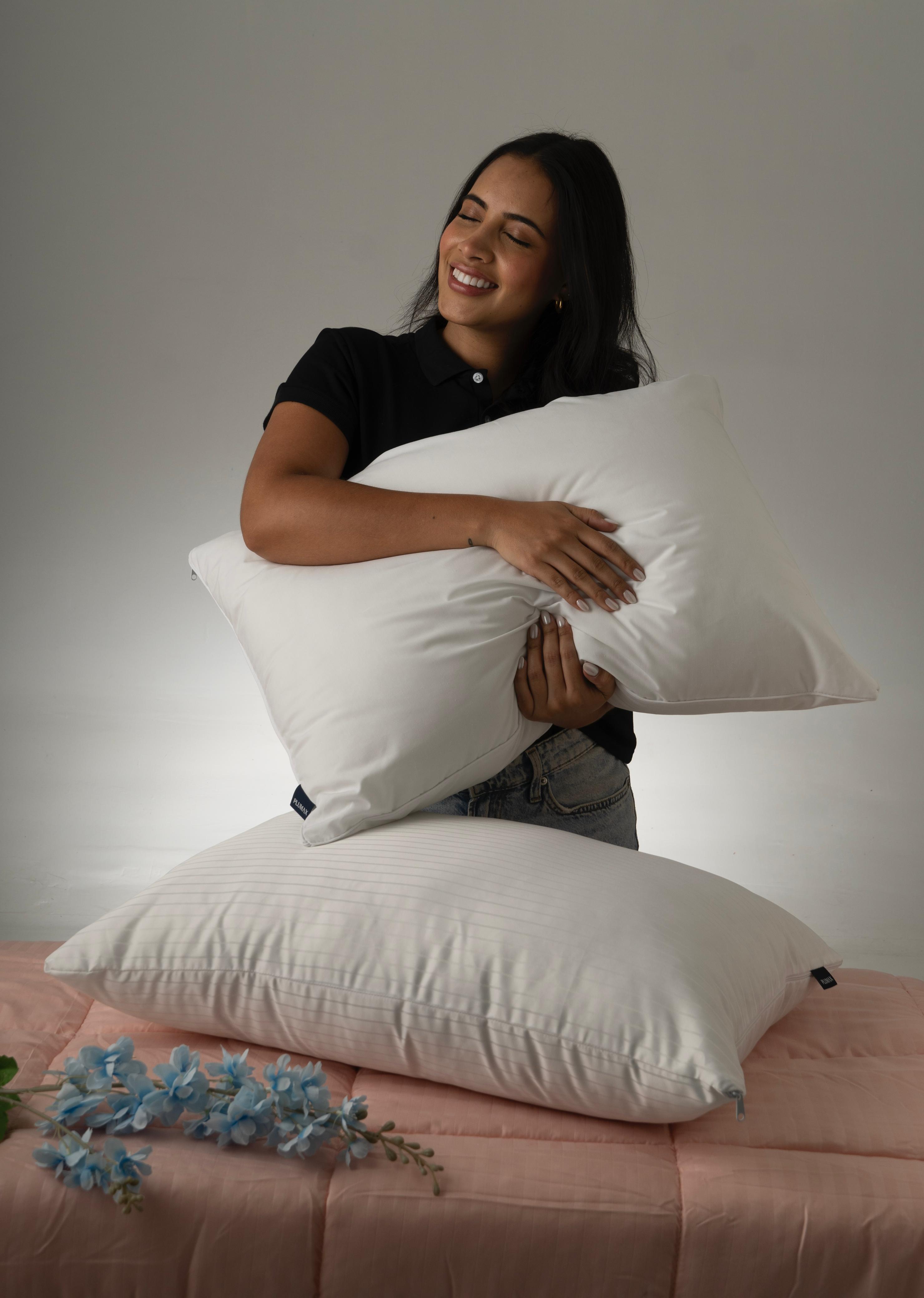 Mujer abrazando una almohada Plumax, transmitiendo confort y suavidad premium para un descanso feliz